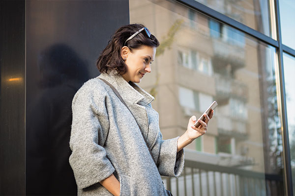 Junge Frau kauft Immobilienfonds direkt am Smartphone Junge Frau kauft Immobilienfonds direkt am Smartphone