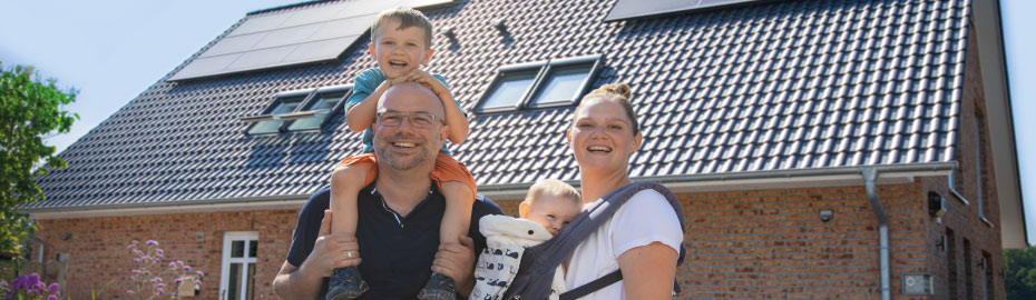 Jetzt Wunschimmobilie finden Junge Familie steht vor Ihrem Wunscheigenheim